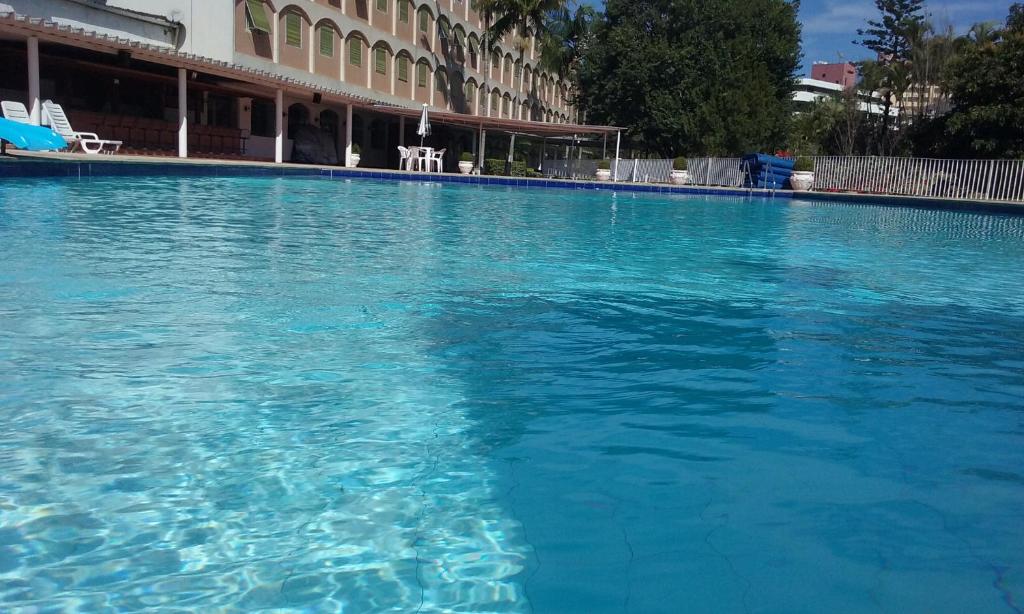 a large pool of blue water in front of a building at Flat Cavalinho Branco (40A) in Águas de Lindóia