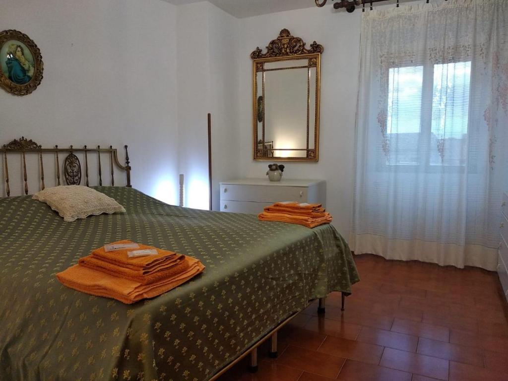 ein Schlafzimmer mit einem grünen Bett und einem Spiegel in der Unterkunft Casa del Ciliegio in Radicofani