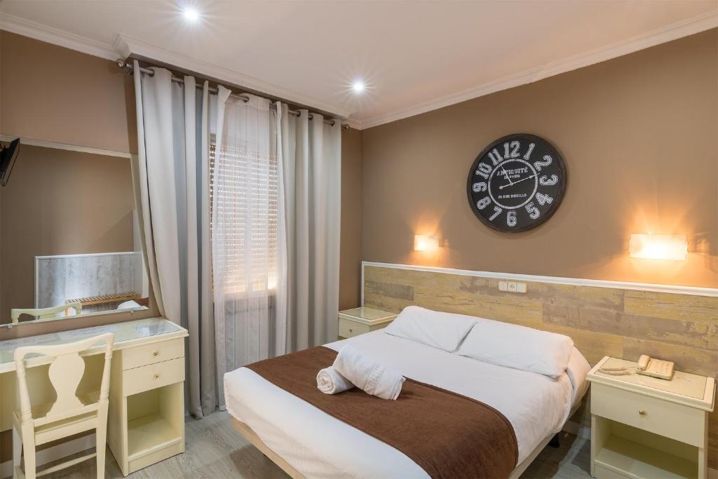 a hotel room with a large bed and a clock on the wall at Hotel Mexico in Madrid