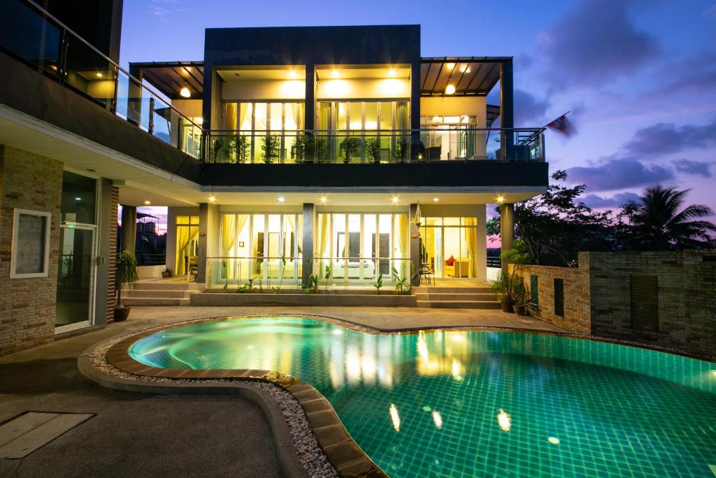 a house with a swimming pool in front of a house at The Ananas Serviced Apartments in Kata Beach