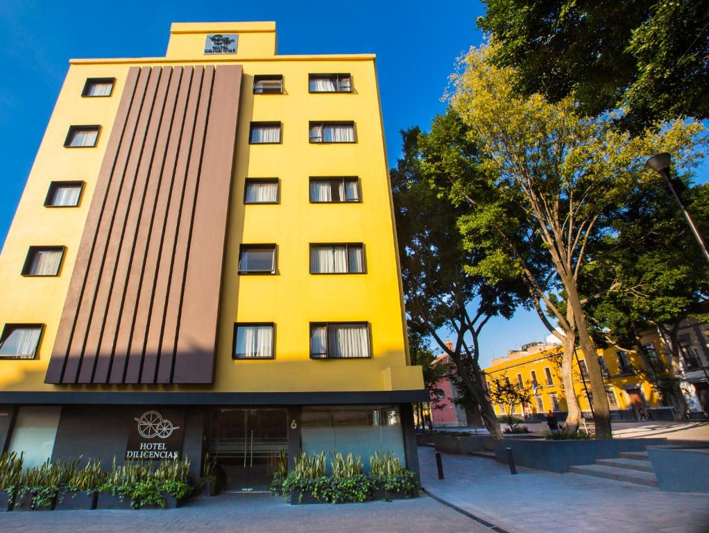 un edificio amarillo con un reloj encima en Hotel Diligencias, en Ciudad de México