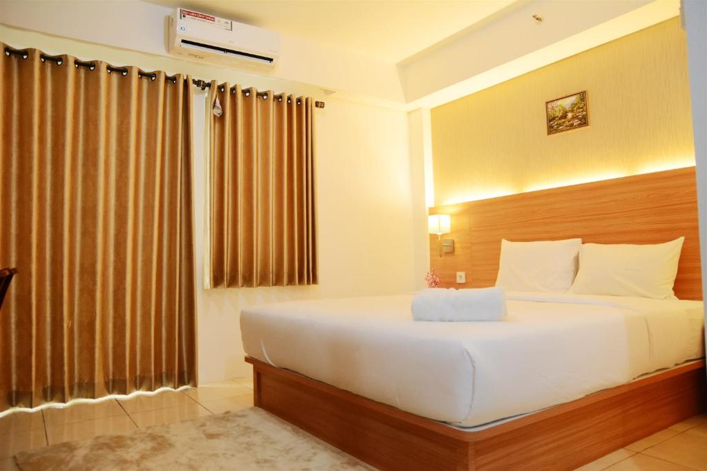 a bedroom with a bed and a large window at Simply Studio Room at Annora Living Apartment Tangerang By Travelio in Tangerang