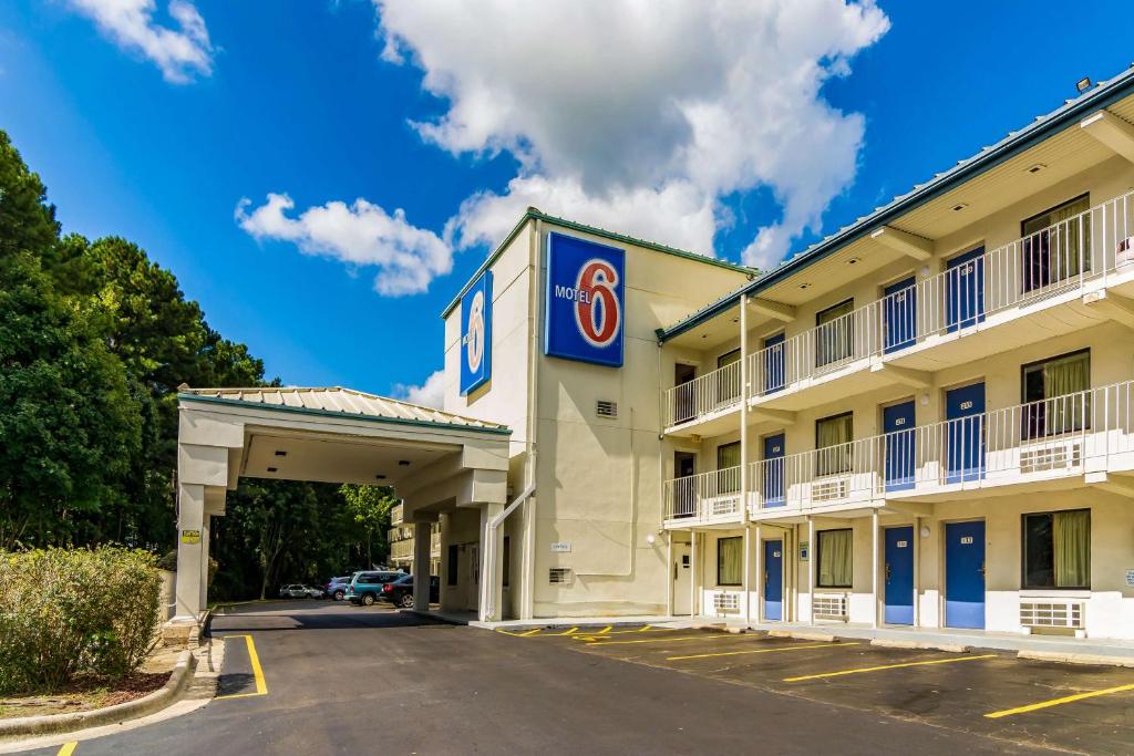 eine Hotelfassade mit einem Parkplatz in der Unterkunft Motel 6-Raleigh, NC - Cary in Cary