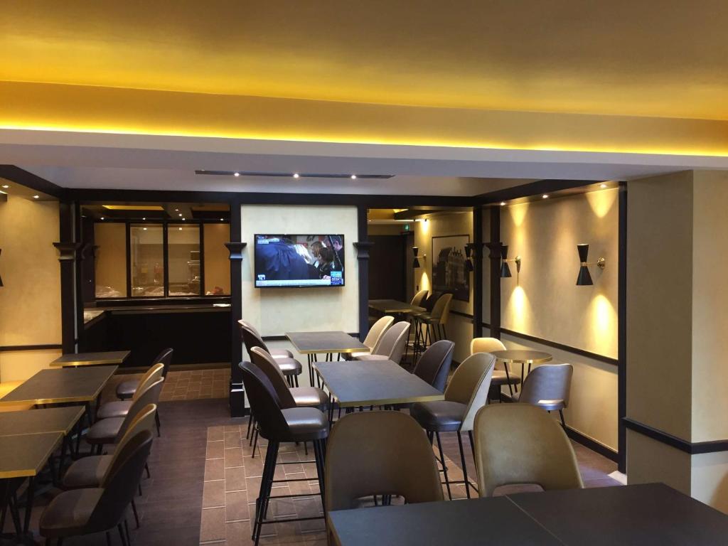 a restaurant with tables and chairs and a flat screen tv at Best Western Select Hotel in Boulogne-Billancourt