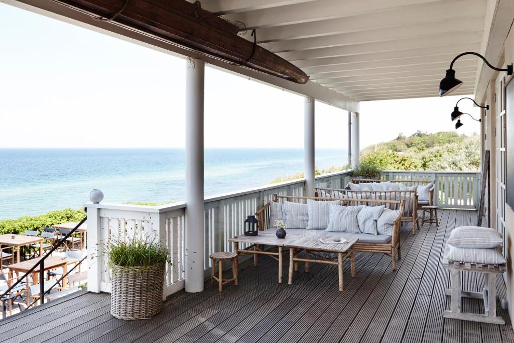 a porch with a couch and chairs and the ocean at Helenekilde Badehotel in Tisvildeleje
