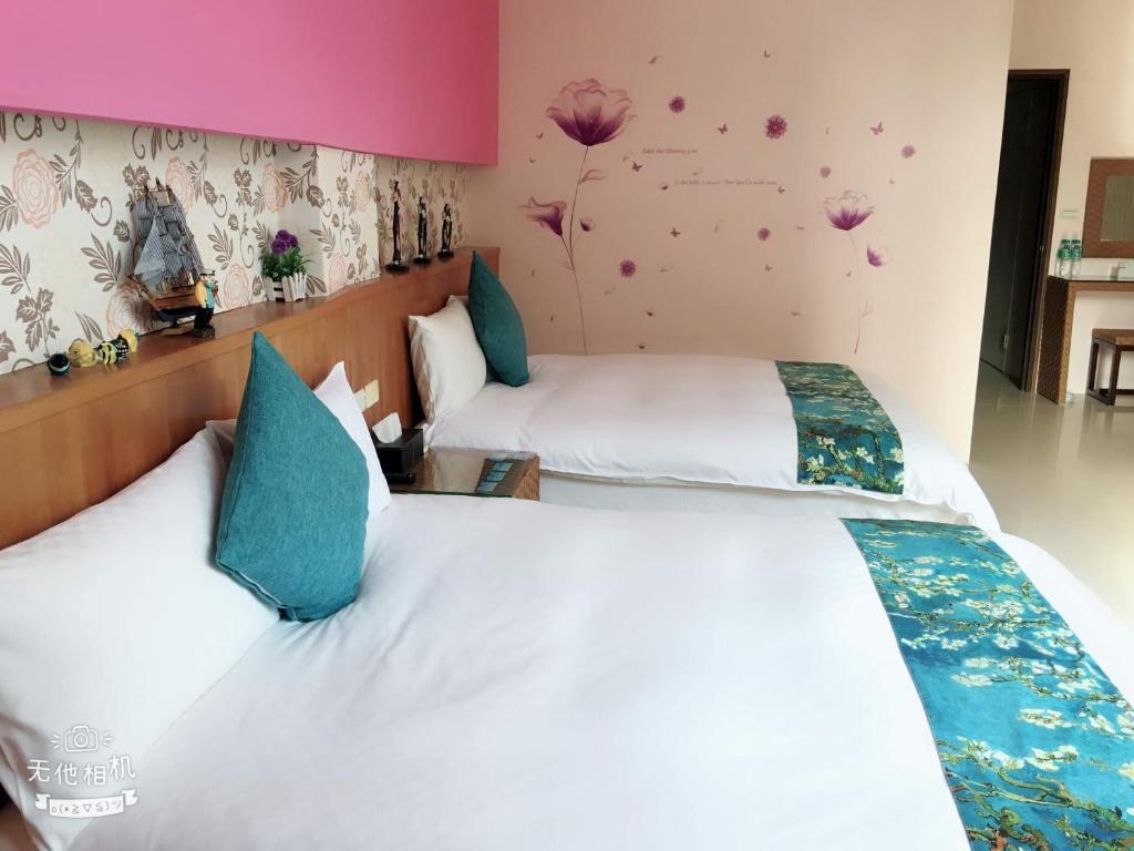 two beds in a hotel room with flowers on the wall at Fish Fun House in Hualien City