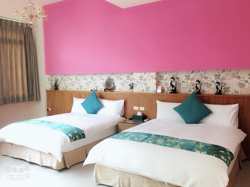 two beds in a room with a pink wall at Fish Fun House in Hualien City