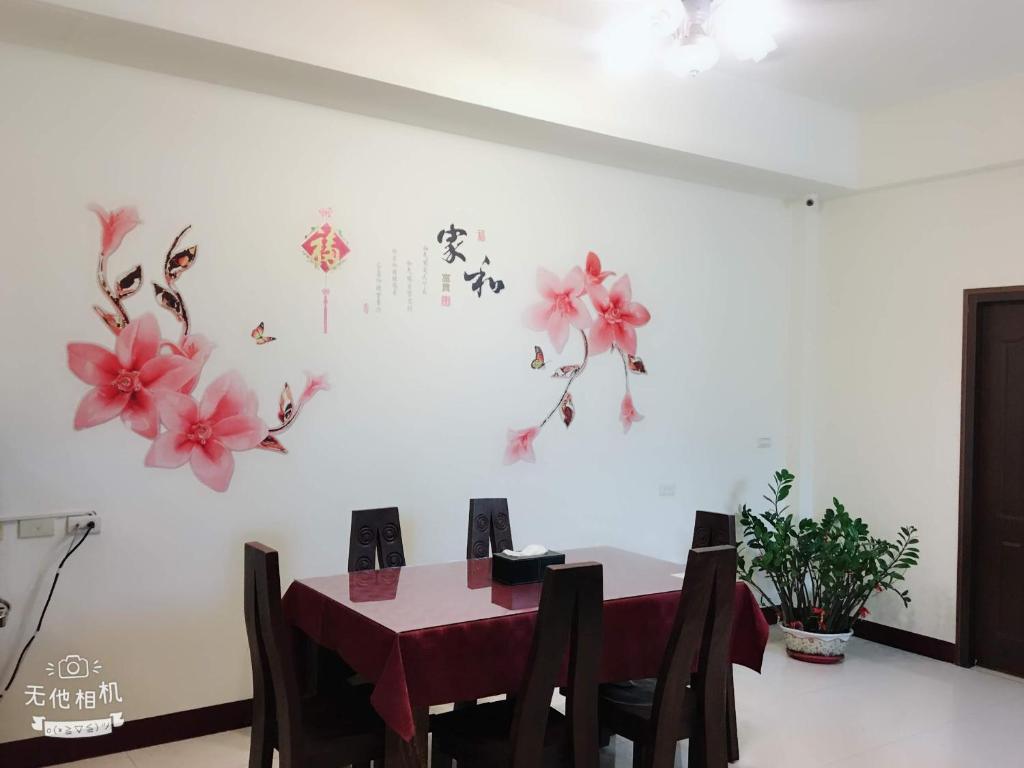a dining room with a table and flowers on the wall at Fish Fun House in Hualien City