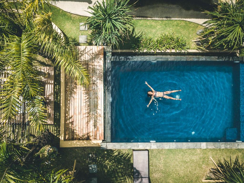a person laying in a swimming pool in the water at Ocho Bali Surf Camp in Uluwatu