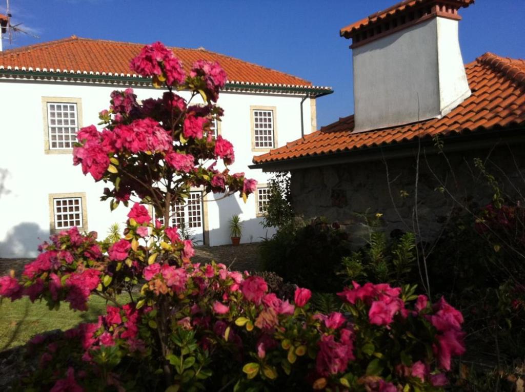 une maison blanche avec des fleurs roses devant elle dans l'établissement Casa Boavista, à Paredes de Coura