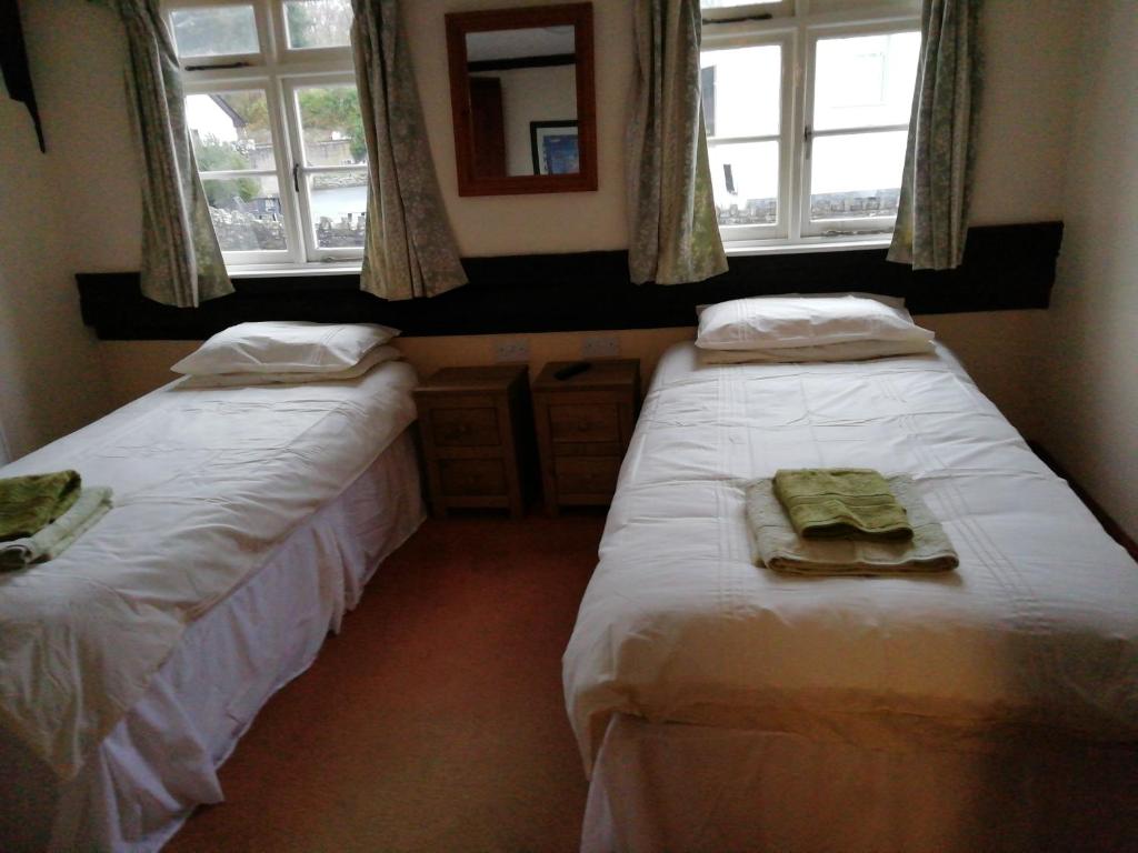two beds in a room with two windows at The Royal Oak in Kington