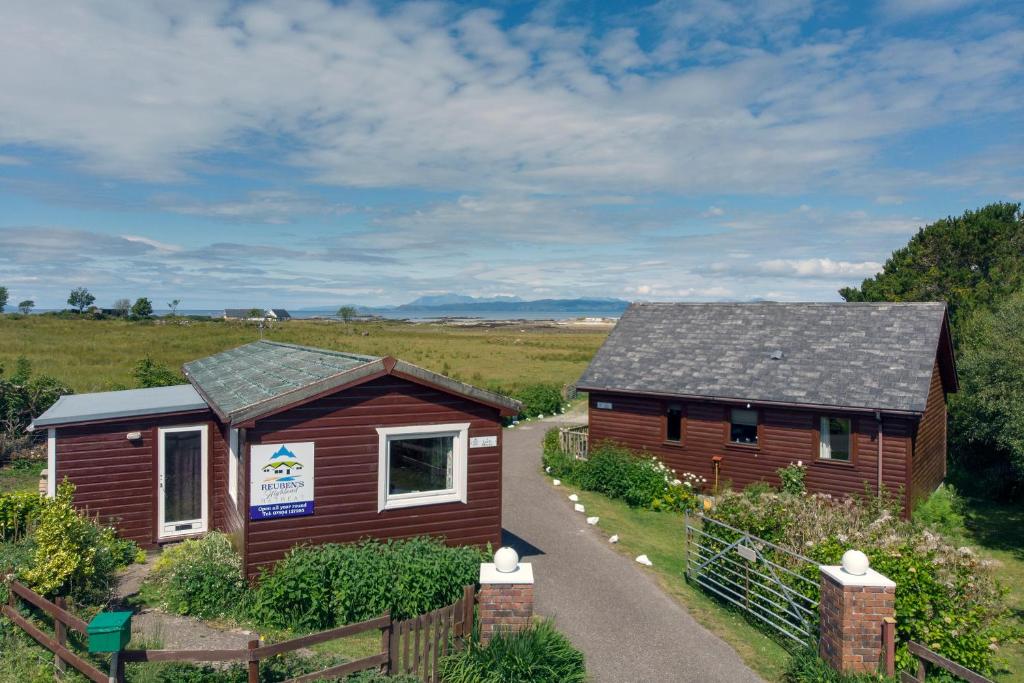 a cabin in a field next to a fence at Reuben's Highland Retreat - Arisaig in Arisaig