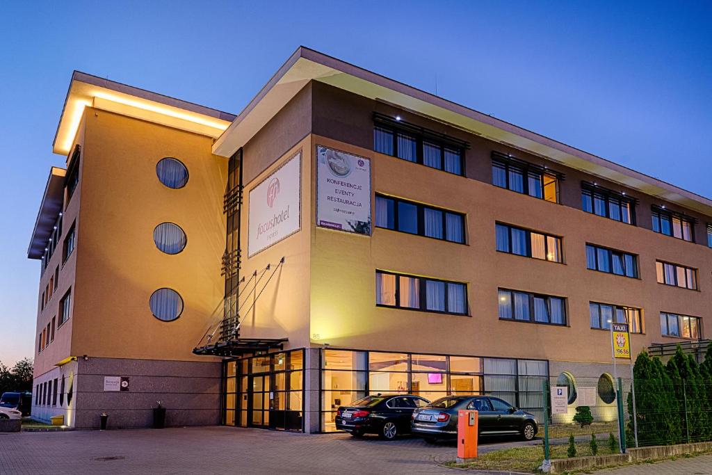a building with two cars parked in front of it at Focus Hotel Gdańsk in Gdańsk
