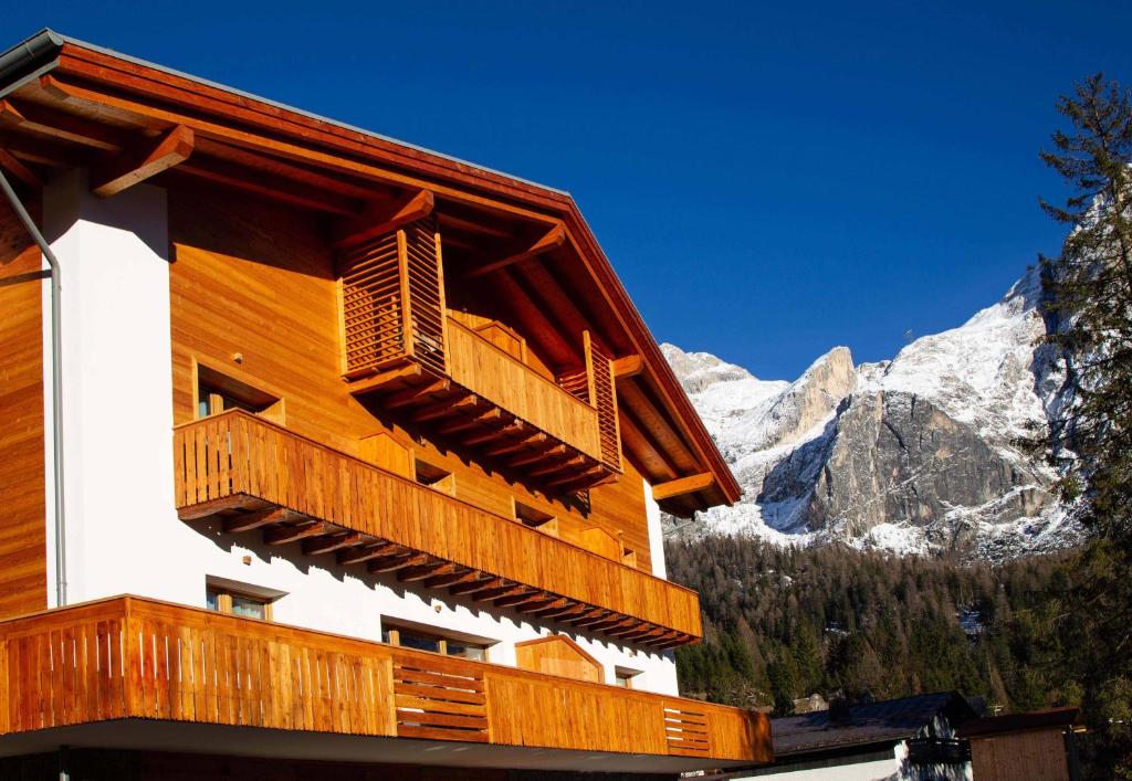 a building with a balcony with mountains in the background at San Martino Mountain Residence in San Martino di Castrozza