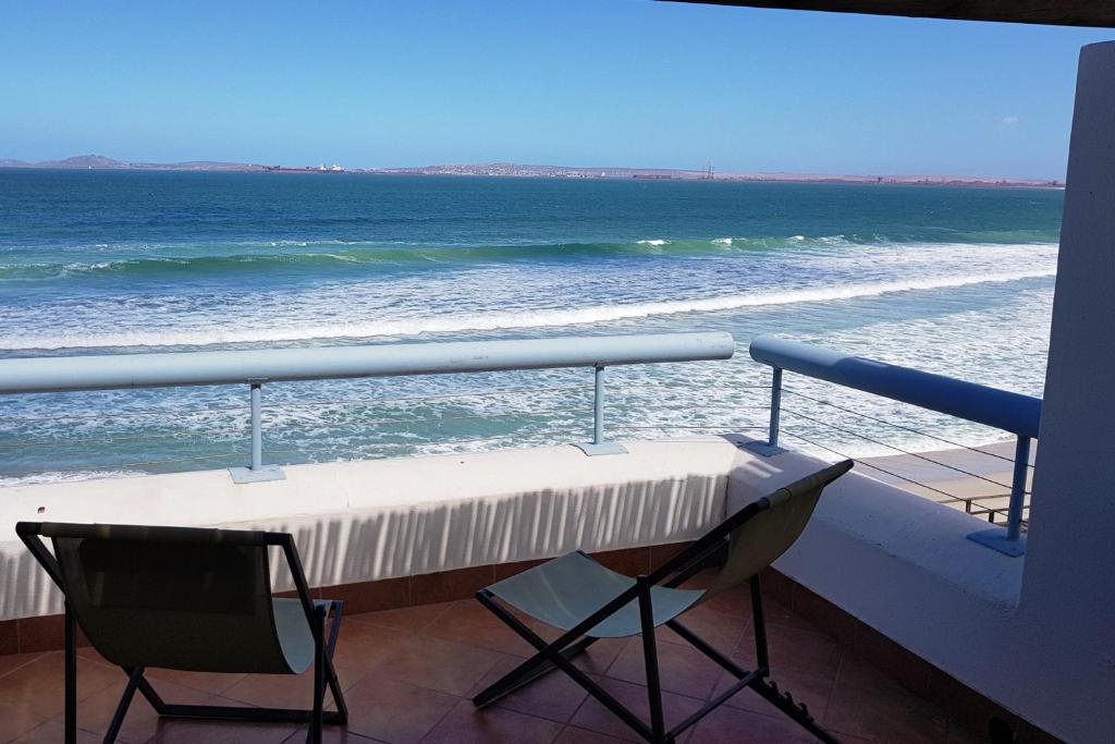 uma mesa e 2 cadeiras numa varanda com vista para o oceano em On the Beach 2 em Langebaan