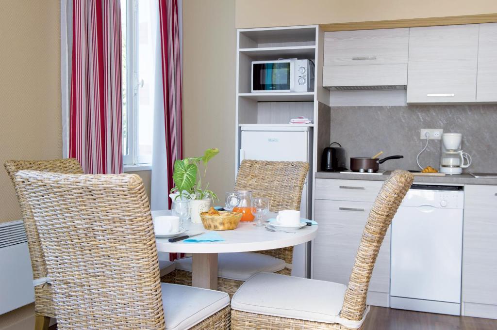 a kitchen with a table and chairs in a kitchen at Résidence de Tourisme Vacances Bleues Villa Regina in Arcachon