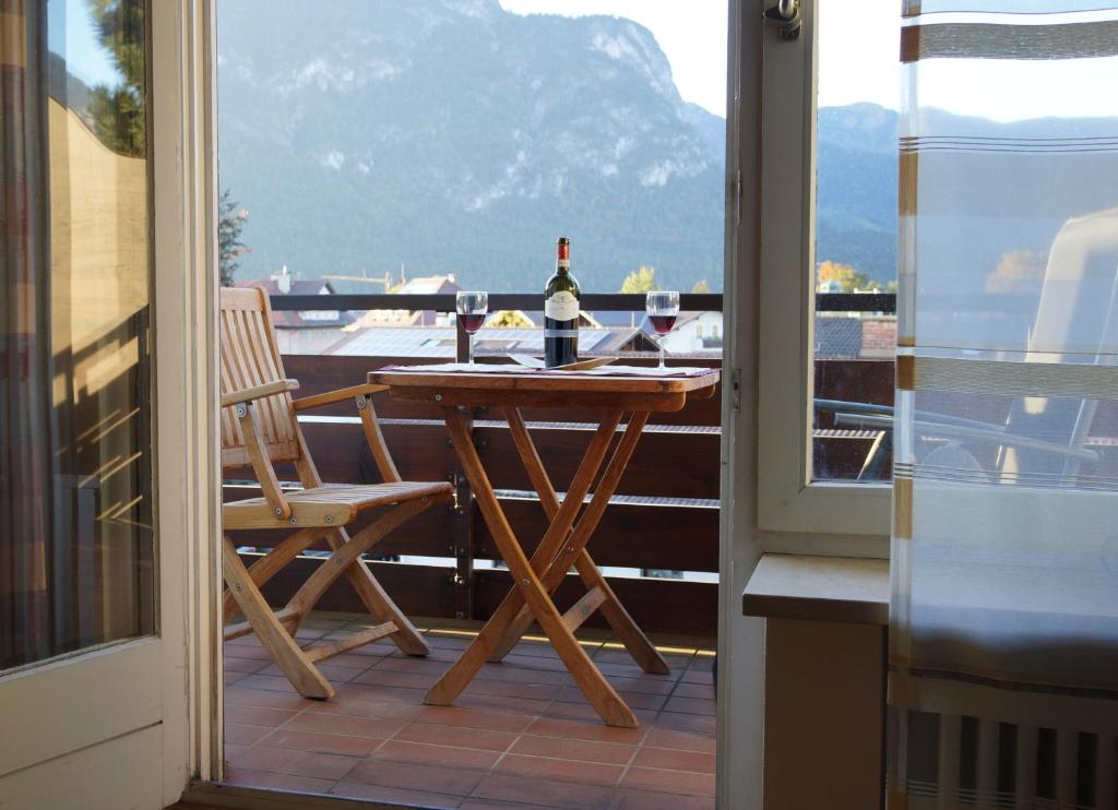 - une table et des chaises sur un balcon avec une bouteille de vin dans l'établissement Sunny 1-room apartment near railway station, à Garmisch-Partenkirchen