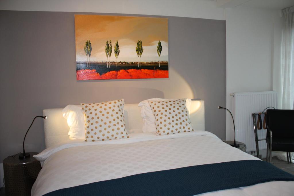 a bedroom with a bed with two pillows and a painting at At number 6 in Amsterdam
