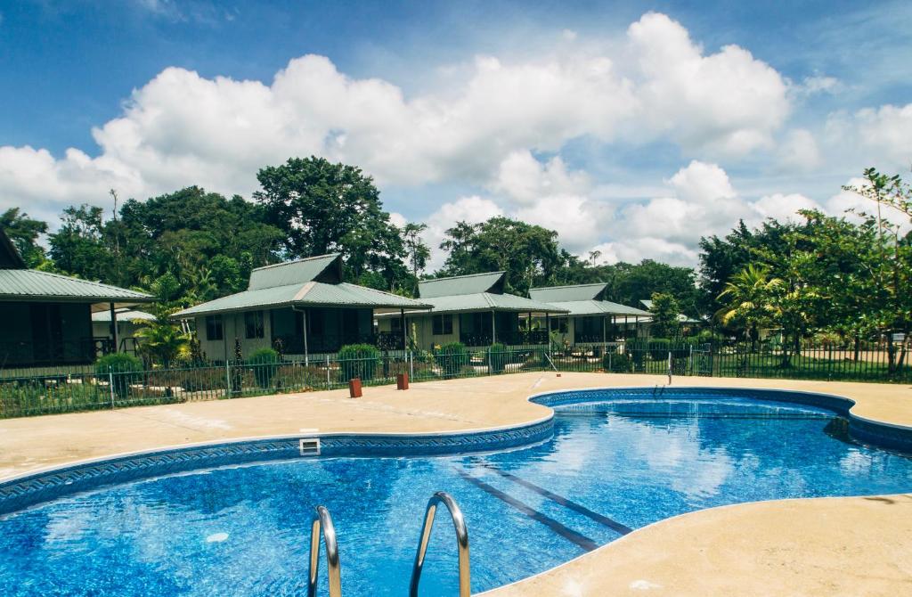 a pool at a resort with trees in the background at Overbridge River Resort in Paramaribo