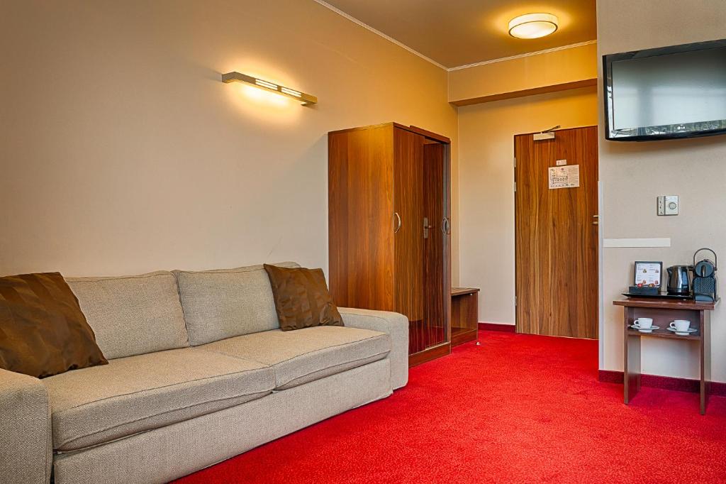 a living room with a couch and a flat screen tv at Focus Hotel Gdańsk in Gdańsk