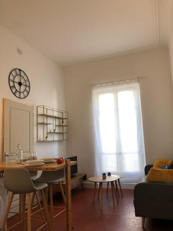 a living room with a table and a clock on the wall at #T2 Intra-muros Avignon in Avignon