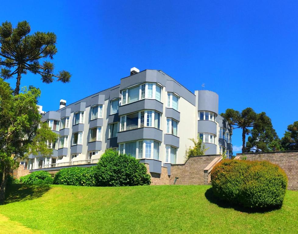 un edificio blanco con árboles delante de él en Flat Mountain Village Luxo e Conforto na Serra, en Canela