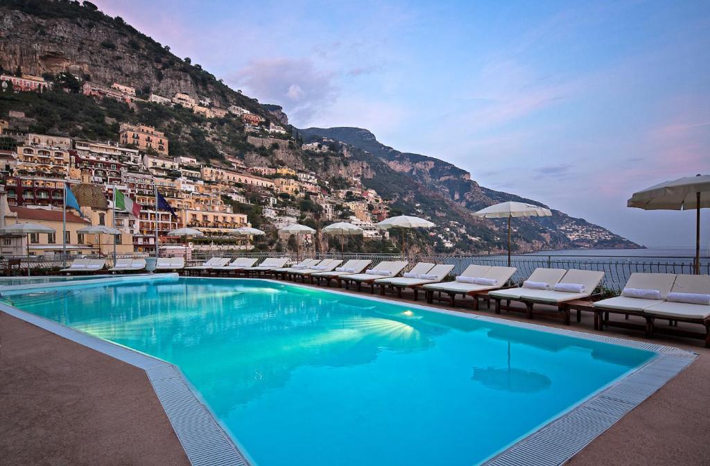a large swimming pool with chairs and a mountain at Covo Dei Saraceni in Positano