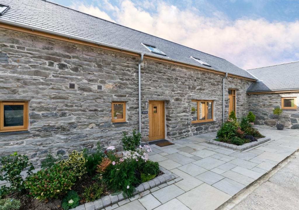 una casa de piedra con un patio frente a ella en Côr Llew Coch, en Bala