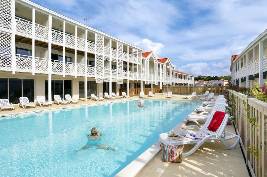 una piscina en un hotel con sillas y gente dentro en Résidence Néméa Les Balcons des Pêcheurs, en Mimizan-Plage