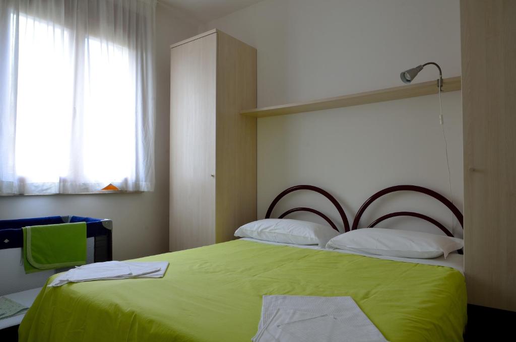 Un dormitorio con una cama verde y una ventana en Aurora Residence, en Lido Adriano