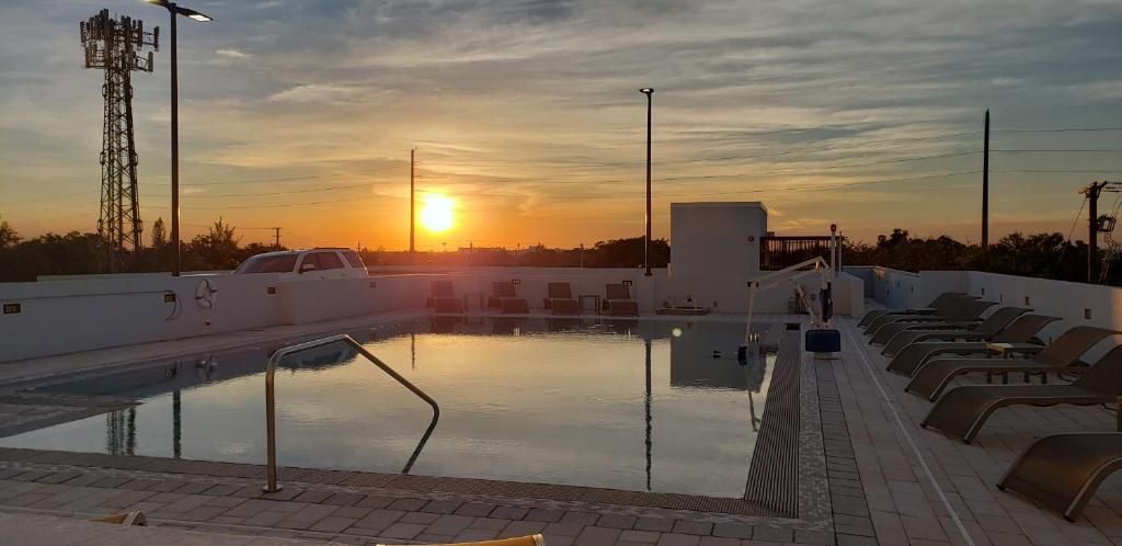 a swimming pool with chairs and the sunset in the background at Wyndham Garden Ft Lauderdale Airport & Cruise Port in Dania Beach