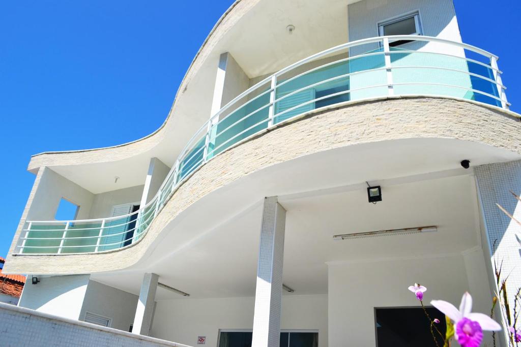 a white house with a blue balcony at Colônia de Férias SITRAEMFA in Peruíbe