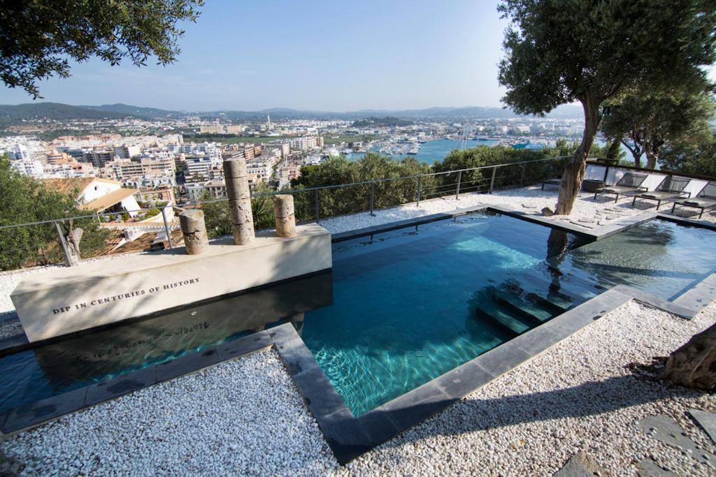 
a large swimming pool with a view of a city at Hotel La Torre del Canonigo - Small Luxury Hotels in Ibiza Town
