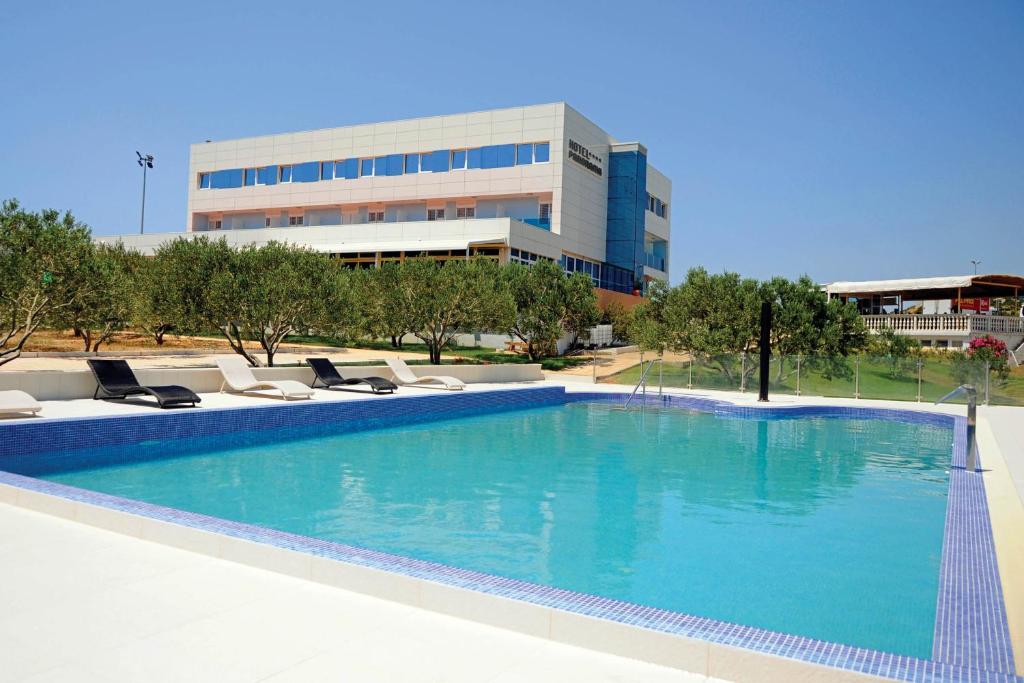 einem großen Pool mit Liegestühlen und einem Gebäude in der Unterkunft Hotel Panorama in Šibenik