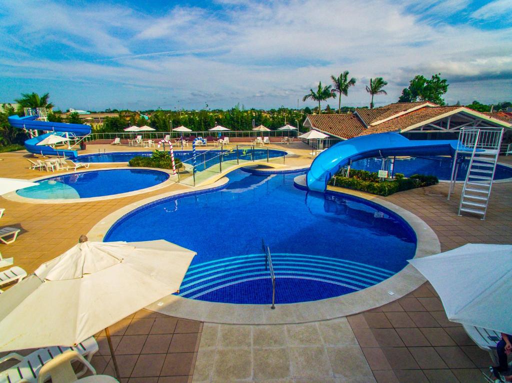 Camboa Hotel Paranaguá في باراناغوا: مسبح كبير مع مظلات في المنتجع