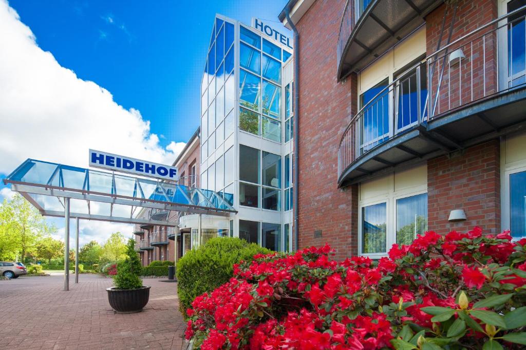 un hospital con flores rojas delante de un edificio en Hotel Heidehof garni en Büdelsdorf