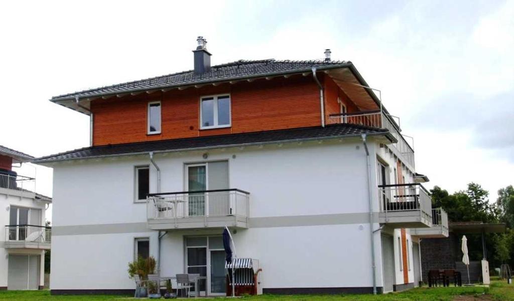 a large white building with a wooden roof at DUENENZEIT App Nr 5 max 4 Pers in Dierhagen