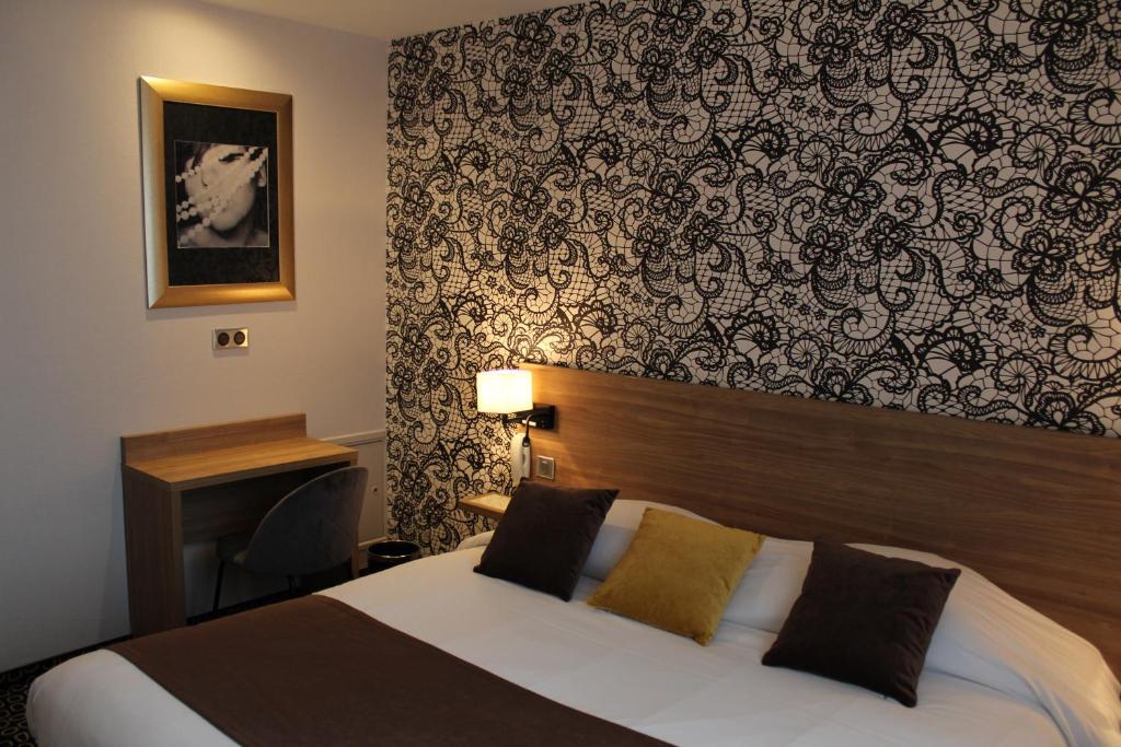 a hotel room with a bed and a wall at In Situ Hotel in Valenciennes