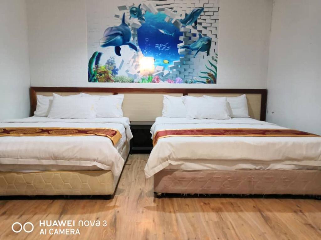 dos camas sentadas una al lado de la otra en una habitación en Mega Inn, en Kuching