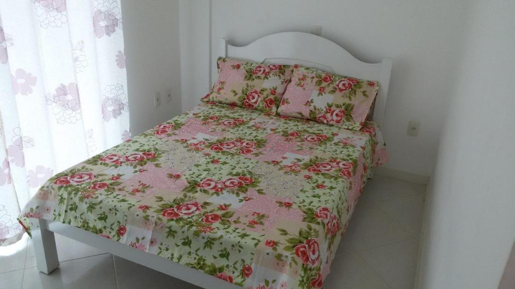 Dormitorio pequeño con cama con colcha rosada de flores en Boulganville, en Bombinhas