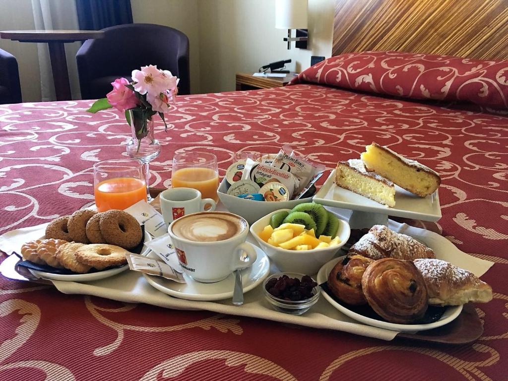 un vassoio di prodotti per la colazione e caffè su un letto di MH Hotel Piacenza Fiera a Piacenza