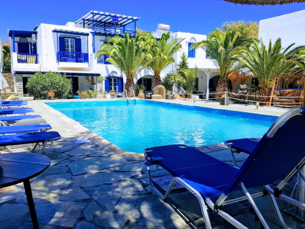 a swimming pool with blue chairs and a building at Tinos apartments Zalonis in Agios Ioannis