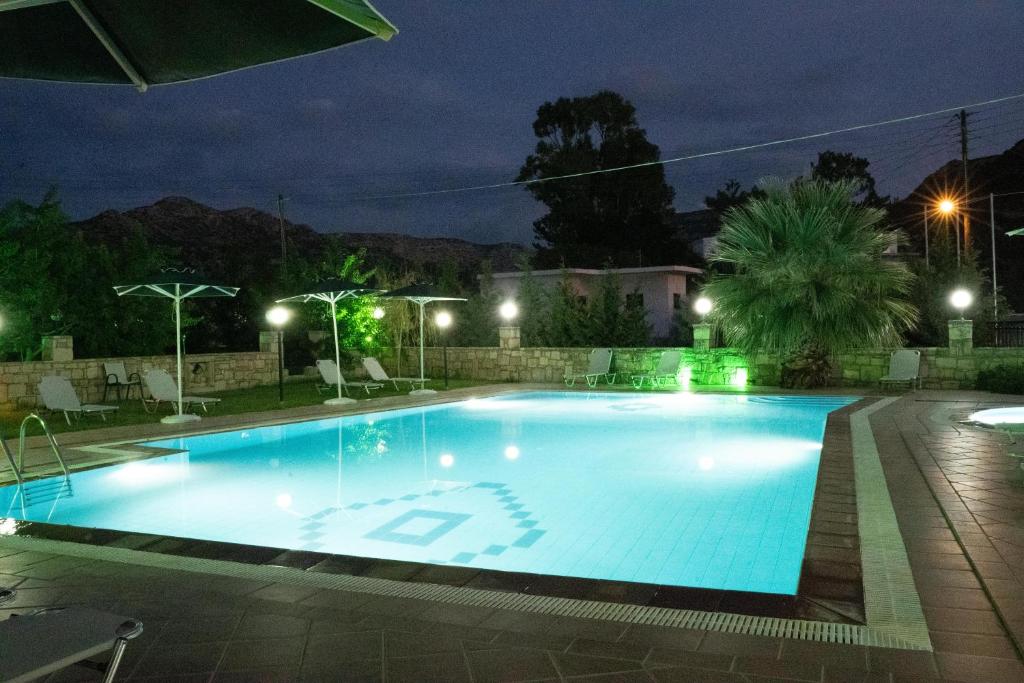 a large swimming pool at night with lights at Dimitris Villa Hotel in Matala