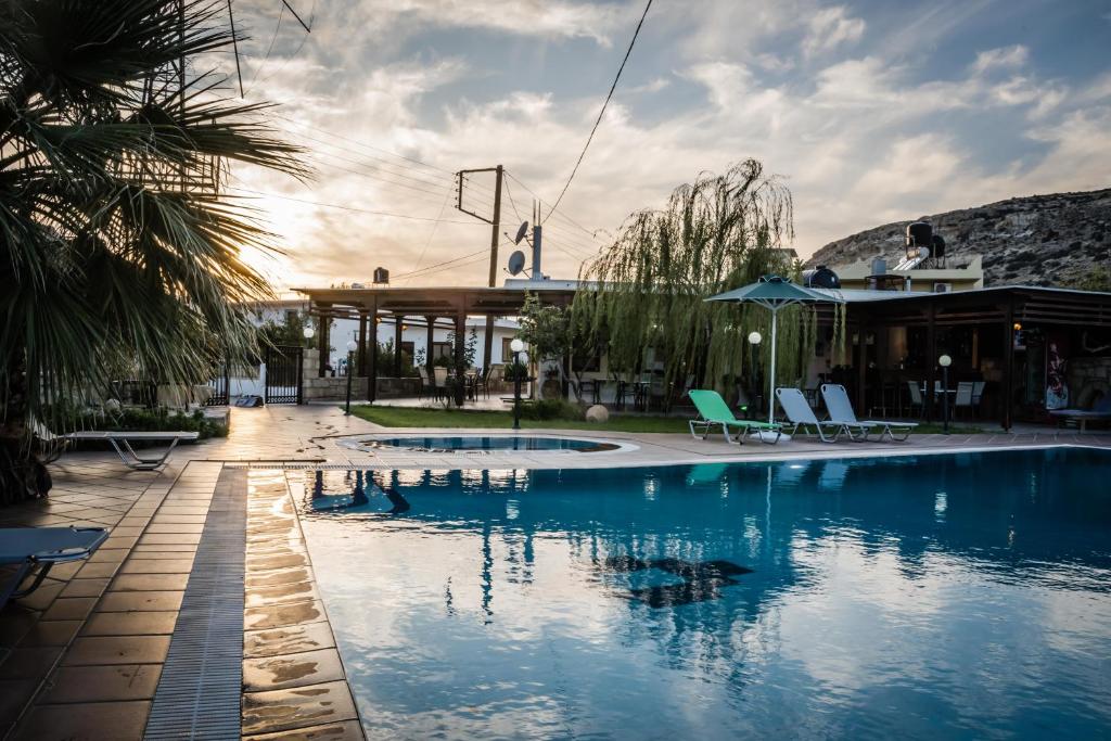 a swimming pool with chairs and a building at Dimitris Villa Hotel in Matala