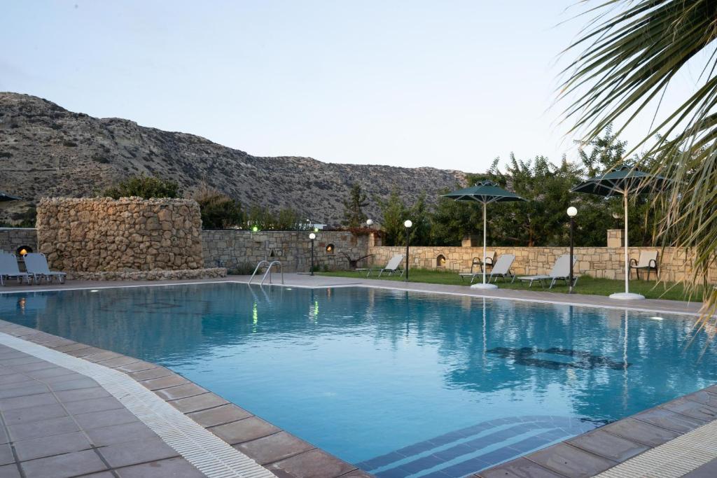 a large blue swimming pool with a mountain in the background at Dimitris Villa Hotel in Matala