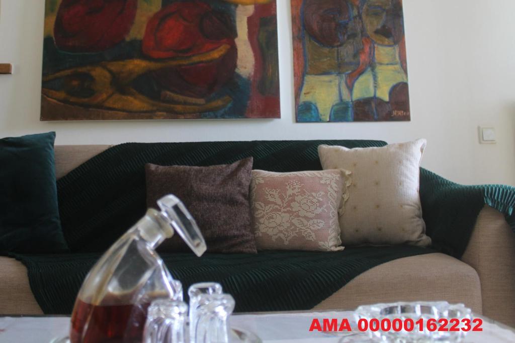 eine grüne Couch in einem Wohnzimmer mit Gemälden in der Unterkunft Traditional House in Peraia