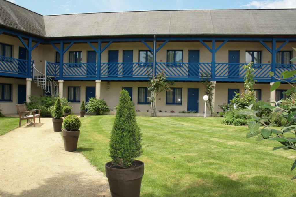 ein großes blaues Gebäude mit Pflanzen davor in der Unterkunft Hotel Capricorne in Vendôme