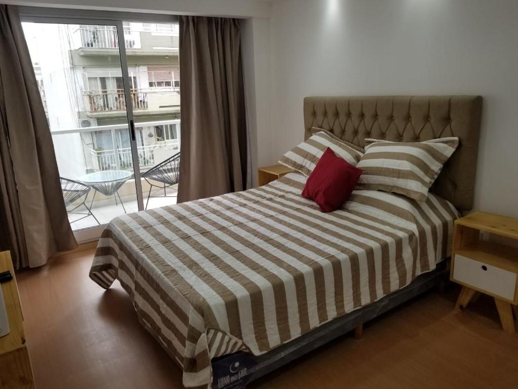 - une chambre avec un lit doté d'un oreiller rouge et d'une fenêtre dans l'établissement Recoleta Unique agüero apartments, à Buenos Aires