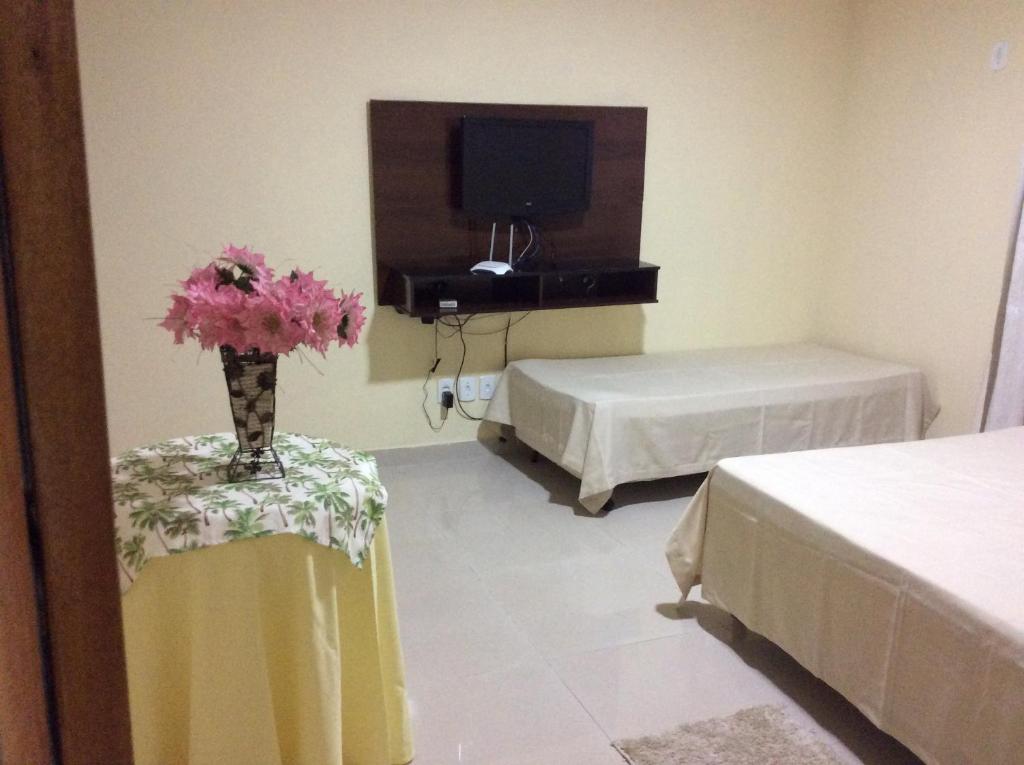 een kamer met 2 bedden en een tafel met een vaas met bloemen bij Apto Praia de Setiba in Una