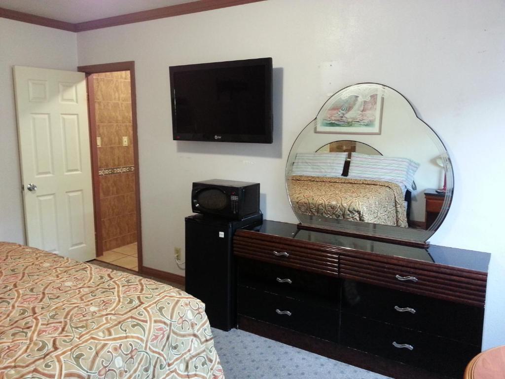 - une chambre avec un miroir et une commode avec un lit dans l'établissement Walls Motel Long Beach, à Long Beach